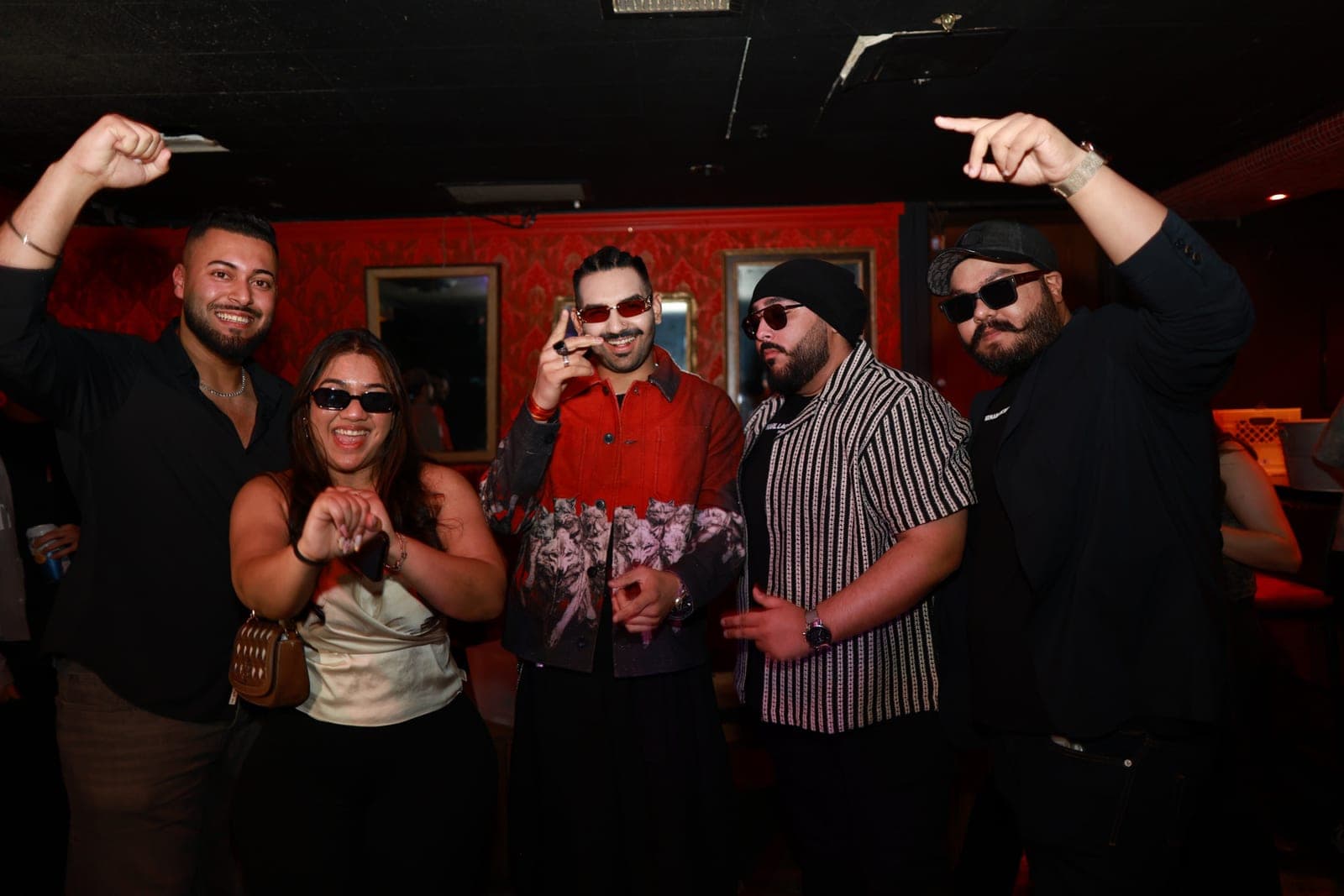 Guests posing in a red-walled club at a Chaska night